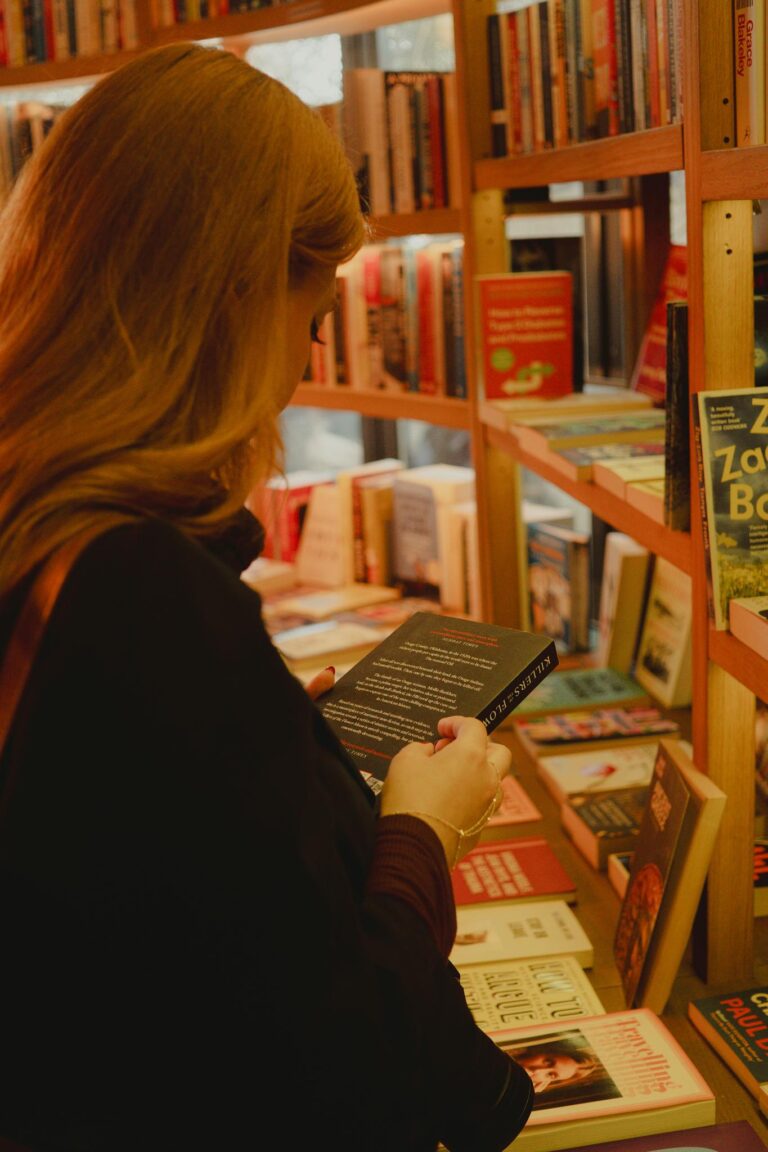 Woman browsing a book in a cozy bookstore filled with shelves of books.